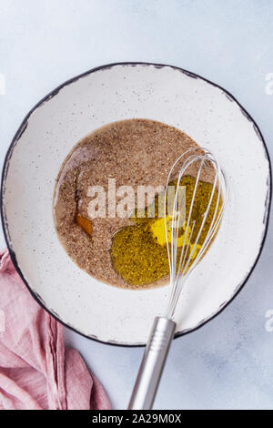 Lino sbattere le uova con lo sciroppo di acero e olio di oliva in una grande ciotola in ceramica Foto Stock