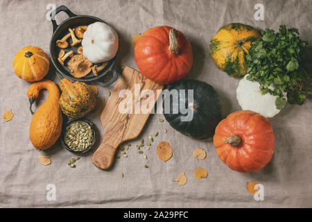 Varietà di zucche colorate, commestibili e decorativo, con foglie di autunno, origano verdi, i funghi finferli, semi di zucca e vuota di taglio di legno Foto Stock