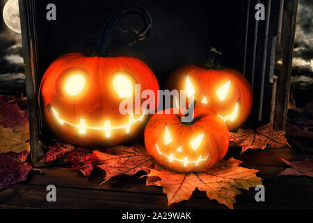 Scary sfondo horror con zucche di Halloween jack o lantern, posto su una gabbia in legno. Foto Stock