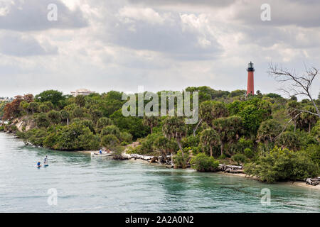 Paddle boarders viaggiare lungo il fiume indiano passato Giove faro di ingresso presso il South Beach ponte di Jupiter, Florida. Foto Stock