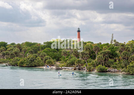 Paddle boarders viaggiare lungo il fiume indiano passato Giove faro di ingresso presso il South Beach ponte di Jupiter, Florida. Foto Stock