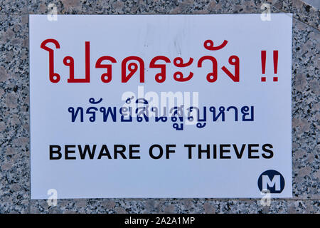 Un cartello bilingue a MRT (metropolitana) Stazione a Bangkok, Thailandia, avverte in Thai e Inglese a diffidare dei ladri Foto Stock