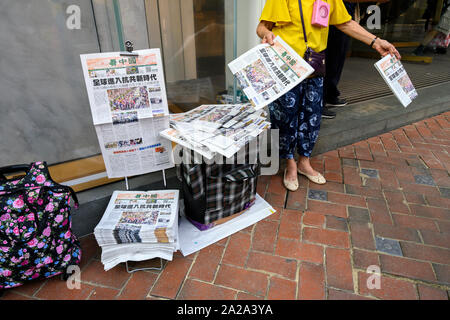 Il 2 ottobre 2019. Hong Kong riprende il business la mattina dopo violente proteste il 1 ottobre 2019. Una donna vende quotidiani rivestimento padiglione la Giornata nazionale di protesta. Foto Stock