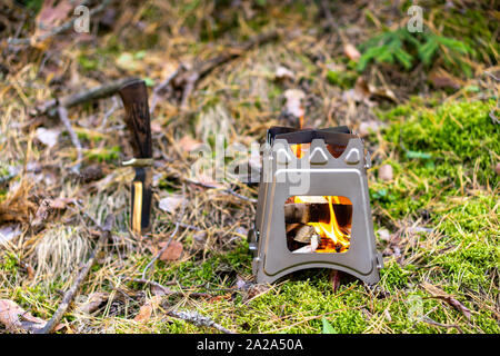 Masterizzazione di legno pieghevole stufa progettato per cucinare all'aperto con ramoscelli come combustibile su sfondo natura Foto Stock