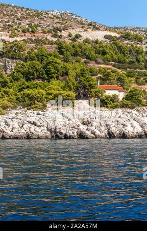 Chiesa sulla costa di Isola di Hvar Croazia. Vista dal mare alla chiesa in Malo Zarace. Chiesa rurale. Vacanze in Croazia. Vista dalla barca a vela. Foto Stock
