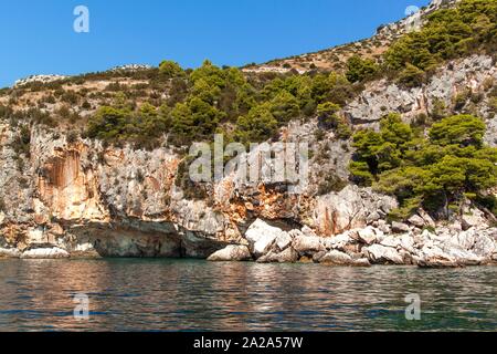 Caletta rocciosa Malo Zarace isola Hvar Croazia - UE. Vacanze in Croazia. Vista dalla barca a vela. Foto Stock