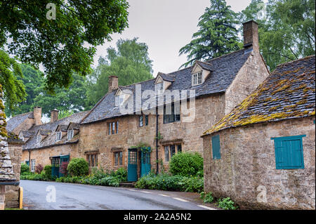 Tipici cottage grazioso con piante rampicanti con giallo Cotswold pareti in pietra calcarea e tetto in ardesia con giardino delle rose in Snowshill, Cotswolds Inghilterra Foto Stock