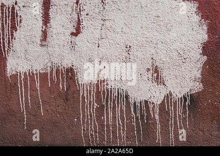 Abstract grunge background. Una macchia di vernice bianca con più macchie sulla intonacata vecchio muro. Parete con vernice rossa. Lungo le macchie di vernice. Foto Stock