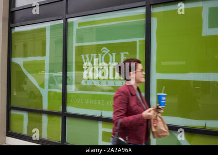 Portland, Oregon, Stati Uniti d'America - Sep 27, 2019: una donna con un to-go borsa per pranzo e una soda al di fuori di un supermercato Whole Foods Market store nel centro di Portland. Foto Stock