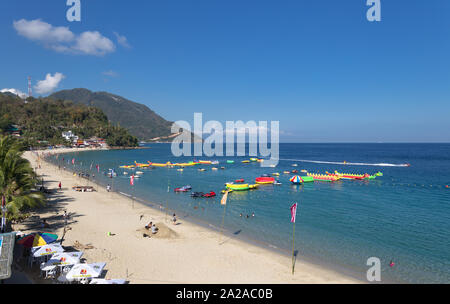 Puerto Galera, Filippine - Aprile 4, 2017: mare, cielo blu, palme, i turisti e le barche in spiaggia bianca, Sabang. Foto Stock