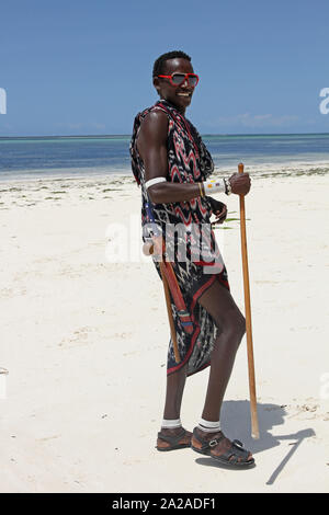 Uomo masai con canna permanente sulla spiaggia, Zanzibar, isola di Unguja, Tanzania. Foto Stock