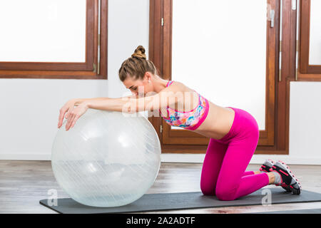 Donna facendo esercizio sulla sfera di pilates Foto Stock