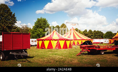 Tenda del circo nel verde della natura con il campeggio rimorchi alberi e cielo blu con nuvole sullo sfondo Foto Stock