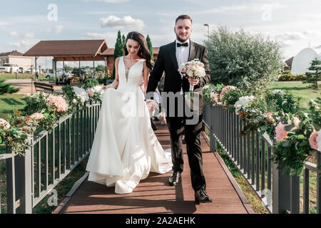 Sposa e lo sposo camminando su un ponte stretto. Feste e tradizioni Foto Stock