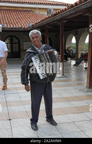 Formare fisarmonica player in area visitatori in Saint Petka Chiesa con gli ospiti seduti intorno, Fortezza di Kalemegdan, Parco Kalemegdan, Belgrado, Serbia. Foto Stock