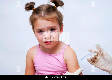 Medico dando un vaccino di iniezione a una bambina. Foto Stock