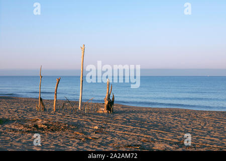 Una scultura di bastoni sulla spiaggia, ramoscelli costruzione sulla spiaggia, bastoni di legno incollato nella sabbia. La land art, sulla costa del mare, seascape in mattinata Foto Stock