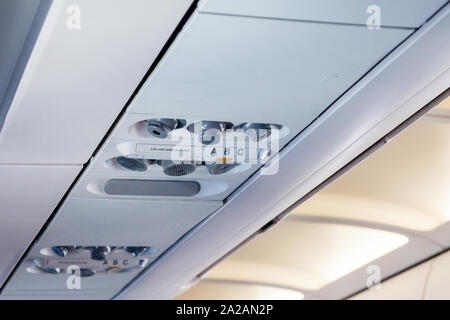 Interior shot di un aereo di linea di passeggeri/velivolo, con i passeggeri seduti sui sedili, con focus principale sul tetto di controlli e pulsanti. Foto Stock