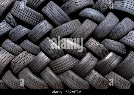 Vecchi pneumatici usati impilati con motivo a spina di pesce Foto Stock