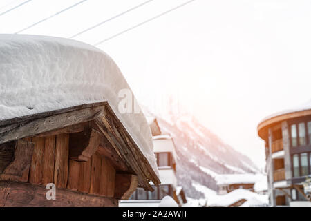 Austrian villaggio alpino paesaggio panoramico con fienile in legno tetto coperto da neve spesso strato dopo la bufera di neve e snowsorm. Foresta di pini e le montagne su Foto Stock