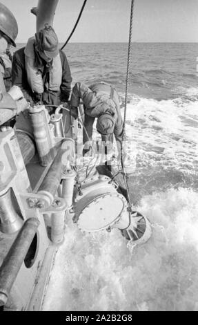 La Lindau classe minehunter costiere durante un esercizio del 6. Minensuchgeschwader (sesta miniera squadrone di spazzamento) nel Mare del Nord. I soldati al lavoro sul minesweeping ingranaggio del prato fiorito. Qui, i soldati tirando fuori un sonobuoy per ripulire il mare miniere con un detonatore acustica. Foto Stock