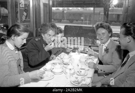 Foto del treno interzonal sulla rotta Leipzig-Gutenfuerst-Hof-Munich. Questo treno era noto per il suo 'tutto-tedesca " auto da pranzo, che è stata molto popolare a causa della 1: 1 tasso di cambio, soprattutto tra Oriente tedesco viaggiatori. Foto del treno passeggeri di bere il caffè e mangiare la torta nella carrozza ristorante. Il est Tedesco ferroviaria dipendente (sinistra) con i suoi due figli si siede a mensa insieme con una donna da Monaco di Baviera e uno studente dal villaggio. Foto Stock