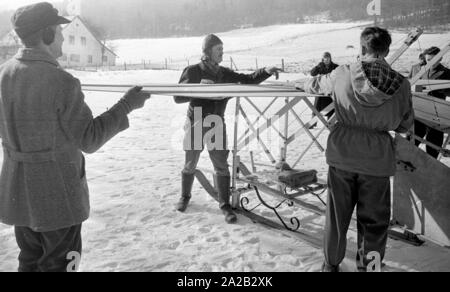 La foto mostra l'hobby-tinkerer Hans Frank (medio) con la sua costruzione che appare come un 'flying sledge'. Apparentemente ha voluto provare la sua costruzione al Hohenbogen ski jump vicino Neukirchen. Il salto con gli sci è stato costruito nel 1952, ma a partire da 1959 nessun Concorsi regolari sono stati detenuti lì e il salto con gli sci è stata demolita negli anni sessanta. Foto Stock