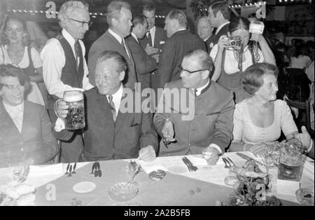 In occasione dell'Oktoberfest in 1970 Willy Brandt è stato ospite nel tendone della Fischer-Vroni. La foto mostra a lui con un boccale di birra, ulteriormente gli ospiti sono seduti intorno a lui. Foto Stock