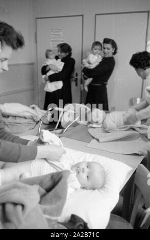 Madri con i loro bambini in vivaio in Rimbach. La donna in primo piano pannolini di un bambino. La comunità del villaggio le case sono state costruite come parte dell'Hessenplan tra gli altri a migliorare le infrastrutture e la vita culturale nelle zone rurali. Foto Stock