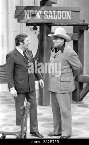 Wim e Thoelke impersonator di Hoss da Bonanza, Dan Blocker, contro lo sfondo di una berlina etichettato 'nuovo salone' sul televisore visualizza 3x9. Foto Stock