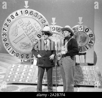 Wim Thoelke e il impersonator di Hoss dalla serie televisiva Bonanza, Dan Blocker, in show televisivo 3x9. Il fortunato ruote nella forma del marchio tedesco e il Pfenning sono i simboli della Aktion Sorgenkind. Foto Stock