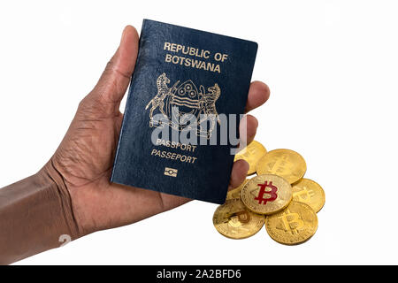 Donna africana mano che tiene un bitcoin e Botswana passaporto africano isolato su bianco Foto Stock