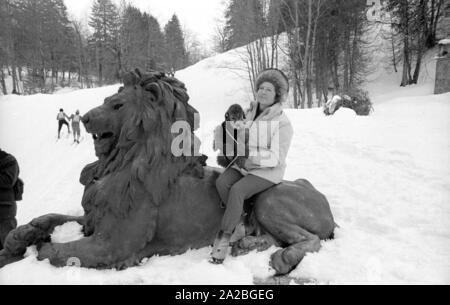 I partecipanti del cross-country concorrenza "Koenig-Ludwig-Lauf' dal Ettal a Oberammergau. Il percorso conduce anche - come mostrato qui - attraverso il parco di Linderhof Palace. In primo piano uno spettatore si siede su uno dei leoni di stagno. Foto Stock