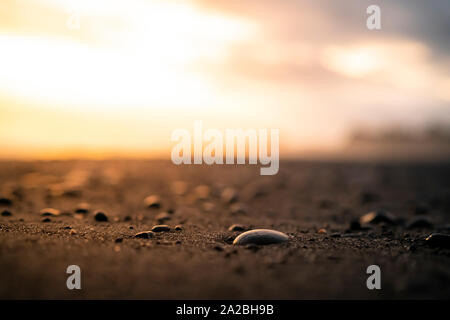 Vicino la spiaggia di ciottoli al tramonto con le onde del mare in lontananza Foto Stock