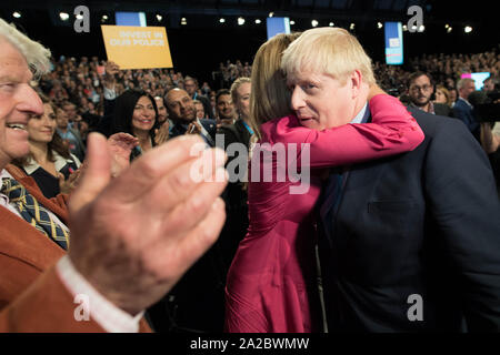 Il primo ministro Boris Johnson è abbracciato dai suoi partner il suo partner Carrie Symonds, dopo aver consegnato il suo intervento durante il congresso del partito conservatore al Manchester Convention Center. Foto Stock