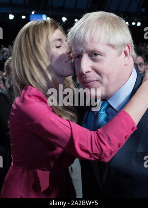 Il primo ministro Boris Johnson è baciata dal suo partner il suo partner Carrie Symonds, dopo aver consegnato il suo intervento durante il congresso del partito conservatore al Manchester Convention Center. Foto Stock