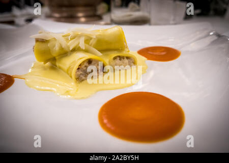 Casalingo Italiano Cannelloni con ricotta, carne di manzo e salsa besciamella, impostazione Gourmet con crema di zucca. Foto Stock