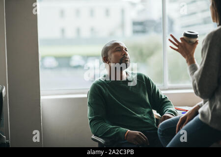 African American designer nel corso di una conversazione con un collega di lavoro Foto Stock