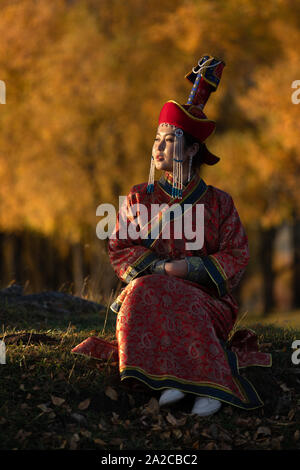 Bella giovane donna in posa tradizionale abito mongolo nella luce del tramonto. Ulaanbaatar, in Mongolia. Foto Stock