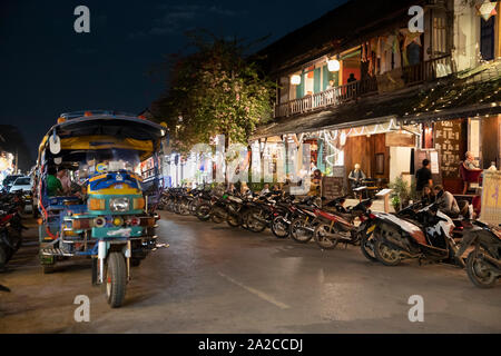 Ristoranti e caffetterie con tuk-tuk lungo Th Sisavangvong di notte, Luang Prabang, Luang Prabang provincia nord del Laos Il Laos, sud-est asiatico Foto Stock