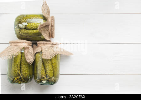 Conserve di verdure cetriolo in vasetti di vetro bianco sulla tavola di legno. Vista superiore dello spazio per il testo. Foto Stock