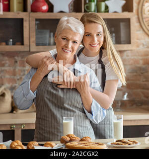 Ritratto di adulto madre e figlia abbracciando in cucina Foto Stock