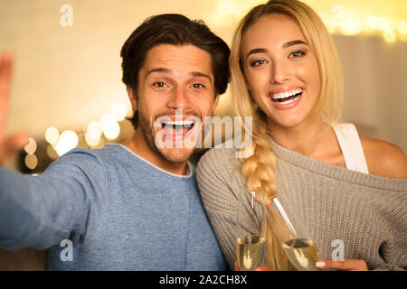 Bella giovane rendendo selfie e tintinnanti bicchieri da champagne Foto Stock