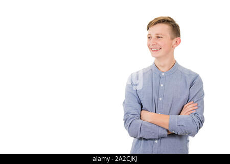 Positivo ragazzo adolescente mantiene con le braccia incrociate guardando oltre il dente sorriso isolate su sfondo bianco con copia spazio. Foto Stock