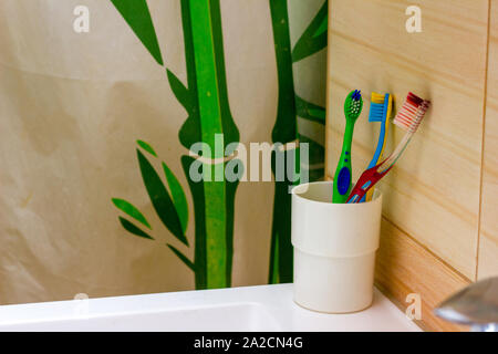 Gli spazzolini da denti si trovano sul lavandino della parete del bagno Foto Stock
