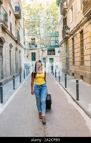 Giovane bella donna latina turistico con una valigia viaggio arriva in una nuova città nei giorni festivi Foto Stock