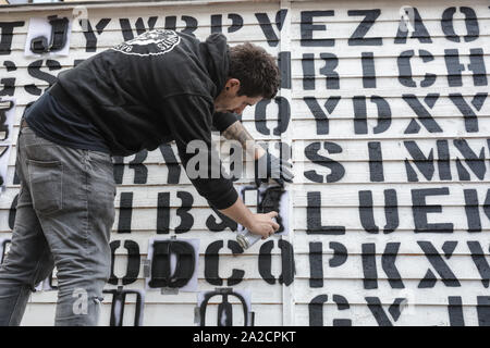 Chelsea ufficio di smistamento, LONDRA, REGNO UNITO, 02 ott 2019. Un artista con ricchi Simmonds arte prepara uno stencil spray pezzo con parole nascoste in una sequenza apparentemente casuale di lettere. Il decimo anniversario di sale di installazione del moniker Art Fair vedere il meglio del British urban artisti, con un roster stellare di creative, compresi acclamati artisti internazionali rendendo il loro regno unito debutti e Moniker's proprio Spotlight artisti del 2019. Credito: Imageplotter/Alamy Live News Foto Stock