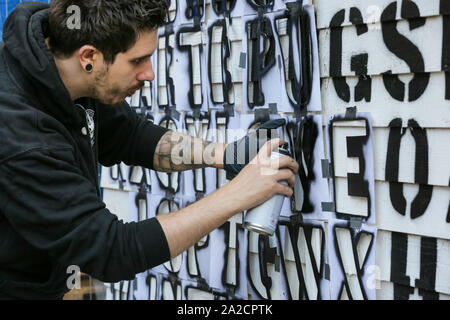 Chelsea ufficio di smistamento, LONDRA, REGNO UNITO, 02 ott 2019. Un artista con ricchi Simmonds arte prepara uno stencil spray pezzo con parole nascoste in una sequenza apparentemente casuale di lettere. Il decimo anniversario di sale di installazione del moniker Art Fair vedere il meglio del British urban artisti, con un roster stellare di creative, compresi acclamati artisti internazionali rendendo il loro regno unito debutti e Moniker's proprio Spotlight artisti del 2019. Credito: Imageplotter/Alamy Live News Foto Stock