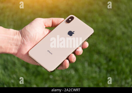 IPhone Xs Max Oro modello dello smartphone da Apple Computer vicino fino in mano maschio sullo sfondo di erba verde. L'Italia, Toscana, Pisa. 26 Dicembre 2018 Foto Stock