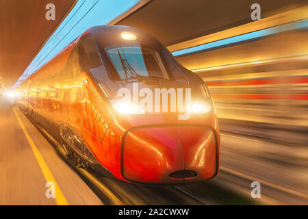 Passeggeri di notte con il treno ad alta velocità che passa dalla stazione in città Foto Stock